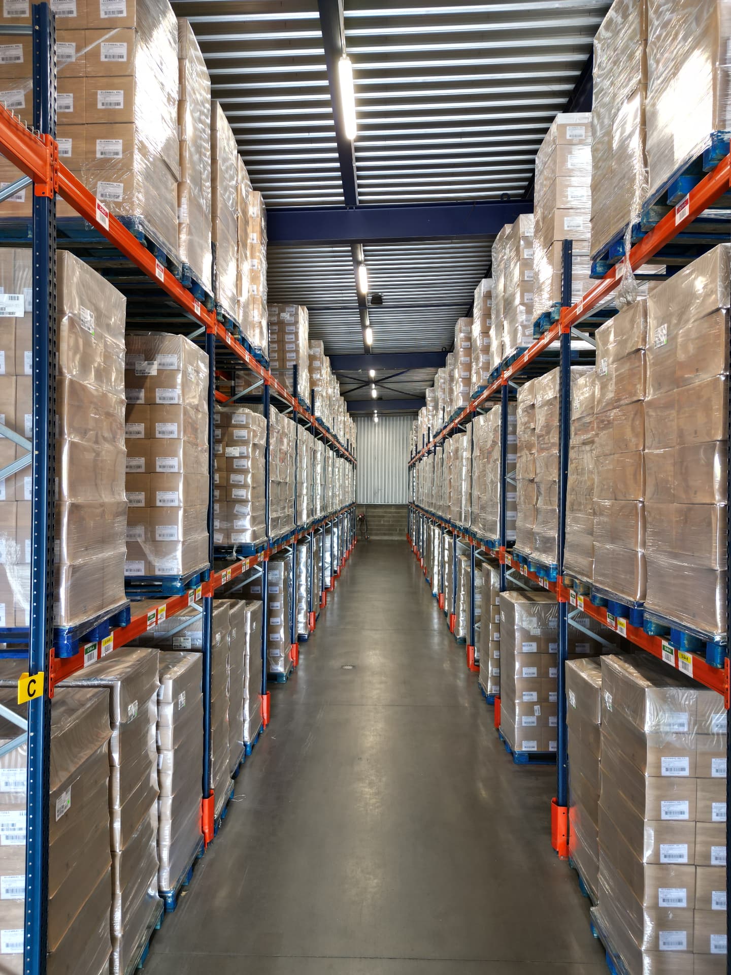 Allée de racks à palettes sur plusieurs niveaux dans l'entrepôt de Sainte-Sigolène